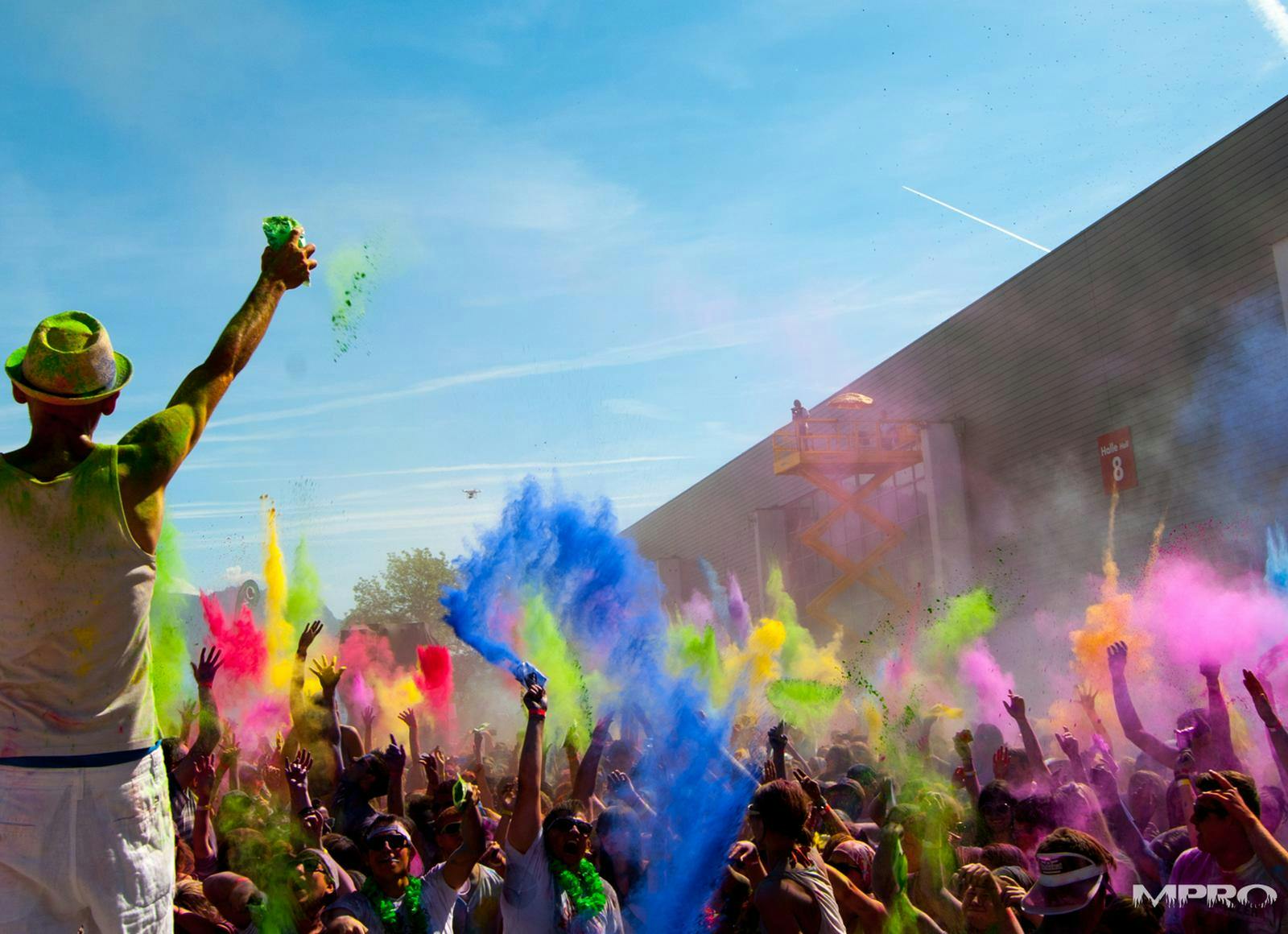 Feiernde Menschenmenge mit bunten Holi-Farben. © 